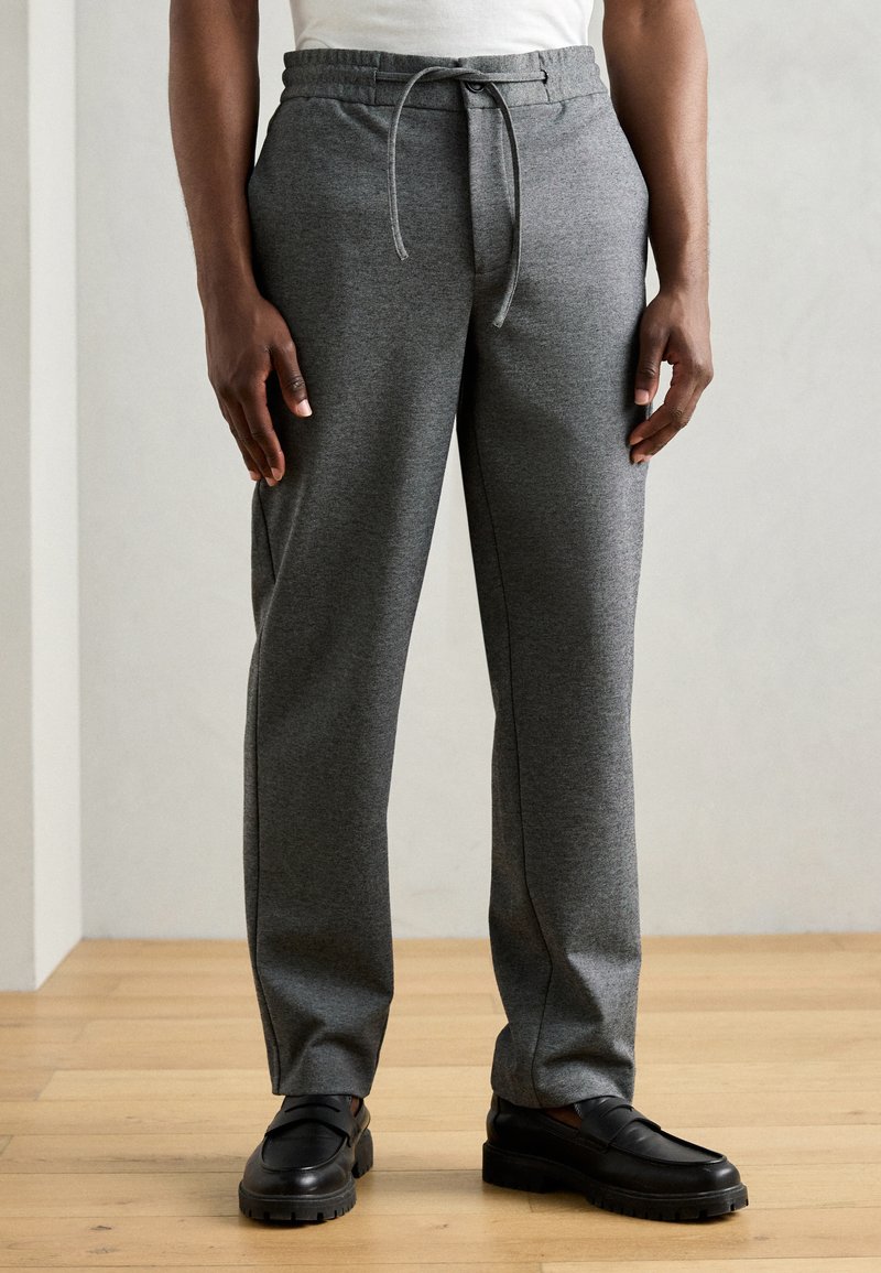 Pantaloni de trening gri, confecționați dintr-un material moale, cu talie elastică și șnur, design cu picioare drepte și buzunare laterale.