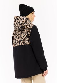 Schwarze Jacke mit einem Leopardenmuster auf dem Rücken und der Kapuze. Das Design bietet eine lockere Passform mit elastischen Handgelenkbündchen und kontrastierenden Texturen.