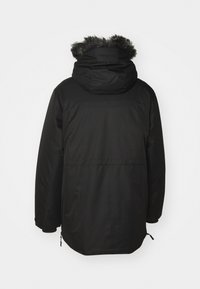 Parka negra con capucha, con un ribete de piel sintética, mangas largas y corte recto. Incluye cordones ajustables en el dobladillo.