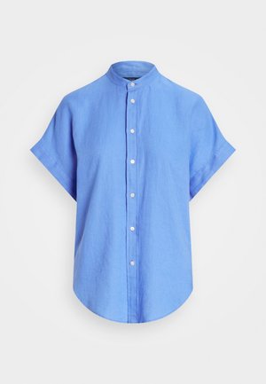 Chemise en lin bleu à manches courtes avec col montant, boutonnière sur le devant, ourlet arrondi et texture lisse. Design minimaliste avec des détails subtils.