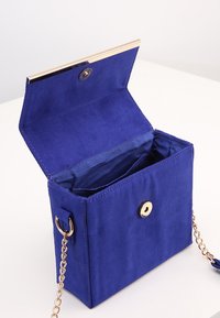 Royal blue torebka z zamszu z zapięciem w kolorze złotym, łańcuszkowym paskiem i otwartym wnętrzem, z gładką podszewką i zapięciem na zatrzask.