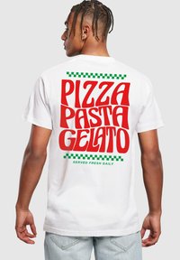 T-shirt en coton blanc avec un texte rouge en gras : "PIZZA PASTA GELATO" avec des accents à carreaux verts et un texte vert plus petit "SERVI FRAIS TOUS LES JOURS."