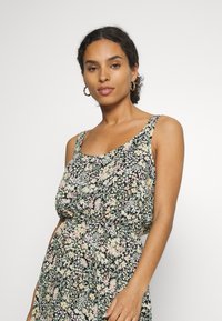 Vestido floral com fundo preto e flores rosa e verdes, alças finas ajustáveis e uma silhueta solta.