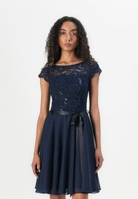 Navy blue dress with a lace bodice, sequins, cap sleeves, and a flowing chiffon skirt, accented with a satin ribbon at the waist.