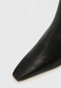 Svart lær sko med spiss tå og en glatt tekstur, med flatt, firkantet tåform og en elegant og minimalistisk design.