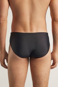 Caleçons de bain noirs en tissu lisse et extensible avec un design ajusté. Caractéristiques d'une taille basse et d'une couverture minimale, mettant en valeur l'arrière.