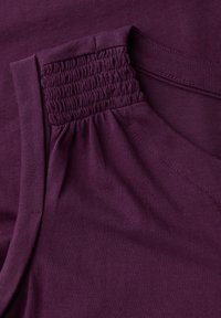 Top in tessuto viola con dettaglio arricciato in elastico sul colletto e superficie liscia. Include una cucitura sottile lungo il lato.
