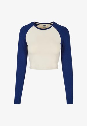 Lühendatud pika varrukaga topp kreemika kehaga ja siniste raglanvarrukatega, valminud pehmest kangast, millel on ümmargune kaelus ja logo silt hemme ääres.