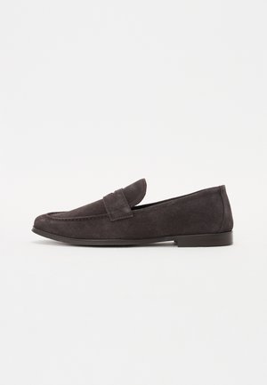 Mocassins en daim gris foncé avec un bout arrondi, des détails cousus et une bande décorative sur le devant. Talon bas en caoutchouc.