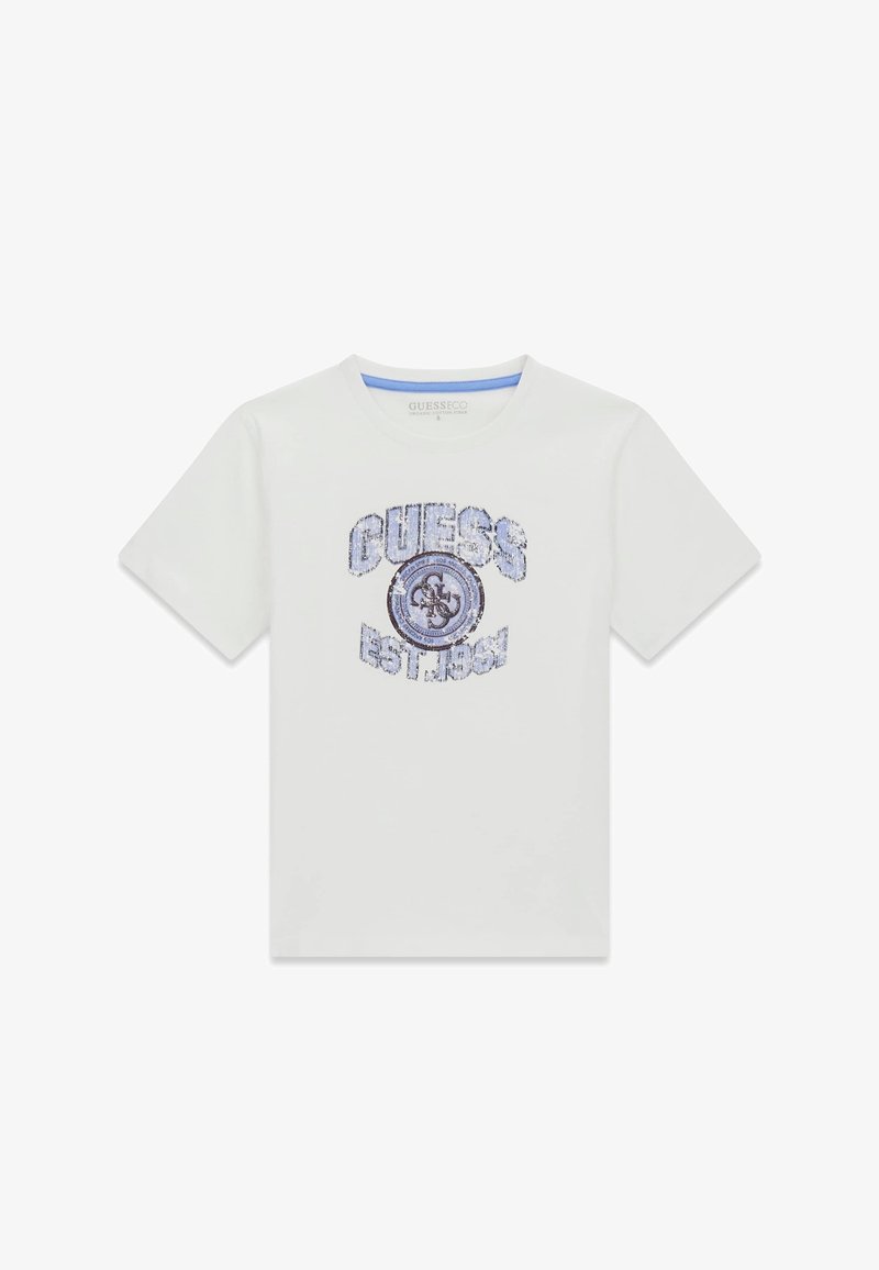 T-shirt blanc à manches courtes avec texte en sequins bleus "GUESS EST. 1981" et logo circulaire au centre, en coton biologique.