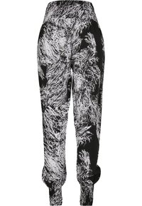 Svarta joggers med ett vitt abstrakt mönster, elastiskt midjeband, avslutade anklar och ett lätt, mjukt tyg.