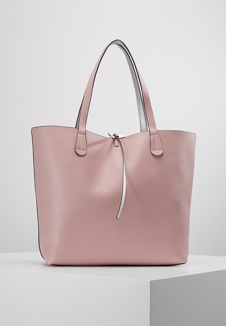 Roze leren shopper met twee schouderbanden. Glad textuur met een subtiele glans en een zilveren ritssluiting bovenaan.