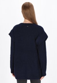 Granatowy sweter z dzianiny o miękkiej teksturze, w luźnym kroju, z krótkimi falbaniastymi rękawami, z małą metką z tyłu przy dekolcie.