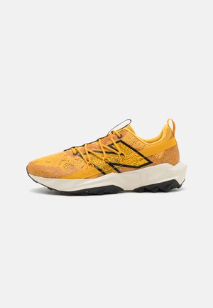 Geel sportieve schoen met een gestructureerde mesh bovenkant, zwarte accenten en een dikke witte tussenzool. Bevat een zwarte rubberen buitenzool voor grip.