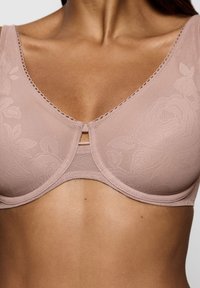 Hellrosa BH aus weichem Spitzenmaterial mit floralen Mustern, einem flachen Ausschnitt und einem einzigen dekorativen Schlüssellochdetail in der Mitte.