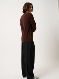 Maglione a maglia marrone con collo rotondo, vestibilità comoda, abbinato a pantaloni neri larghi. Tessuto liscio, design semplice, palette di colori neutri.