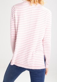 Rosa och vitrandig långärmad topp med rund hals. Mjuk textur, ribbat nederkant och en sömdetalj som löper ner i mitten.