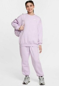 Lila sweatshirt och matchande sweatpants i mjukt material. Har ribbade muddkanter och en liten vit logotyp. Bärs med silverfärgade sneakers.