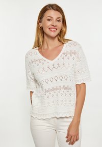 Top bianco lavorato a maglia con scollo a V, maniche corte e motivi a traforo; con orlo ondulato e una finitura testurizzata.