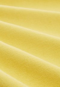 Gelber Stoff mit glatter Textur, der diagonale Rippmuster und einen leichten Glanz durch geknautschte Falten aufweist, was die visuelle Tiefe verstärkt.