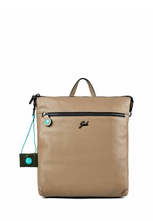 Beiger quadratischer Lederrucksack mit vorderer Reißverschlusstasche, kleinem oberen Tragegriff und schwarzem Logo-Detail, mit einem türkisfarbenen Anhänger auf der linken Seite.
