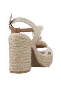 Sandal de tacón alto en color beige con plataforma de yute trenzado, correas anchas y una correa para el tobillo con hebilla. Acabado texturizado, tacón resistente.