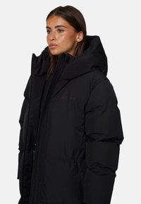 Czarna kurtka puchowa z wysokim kołnierzem i kapturem. Posiada gładką teksturę, zamek błyskawiczny z przodu oraz elastyczne mankiety. Minimalistyczny design z brandingiem.
