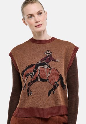 Femme portant un pull sans manches en maille marron avec un motif de cowboy montant un cheval cabré sur le devant.
