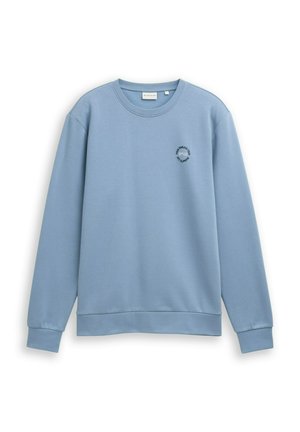 Sweatshirt de culoare albastru deschis, cu mânecă lungă și guler rotund, cu manșete și tiv din tricot, având un mic logo circular pe pieptul stâng care spune "Tom Tailor Team 1962."