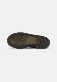 Suela de zapato de goma negra con una superficie texturizada, que presenta un patrón de dibujo para tracción y un diseño de borde liso.