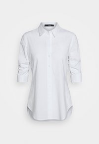 Camicia bianca con colletto, maniche lunghe e dettagli arricciati ai polsini. Realizzata in tessuto liscio con una vestibilità sartoriale e orlo arrotondato.