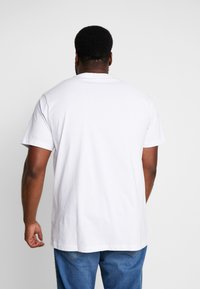 T-shirt blanc à manches courtes avec un col rond, en coton, présentant un ourlet droit et une coupe décontractée, vu de dos.