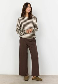 Un haut rayé à manches longues en crème et marron associé à un pantalon large marron. Le tissu semble doux ; le haut présente une coupe décontractée et un col rond.