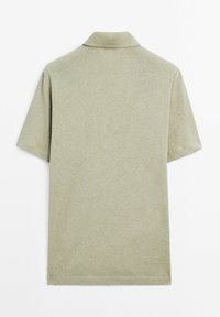 Polo a maniche corte in tessuto verde chiaro con finitura testurizzata, dotato di un colletto classico e orlo dritto. Nessun motivo o dettaglio visibile.