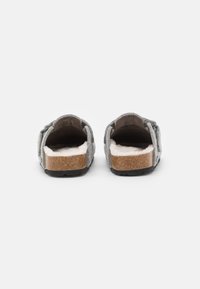 Gray felt slippers with a soft, white inner lining, cork footbed, and black rubber sole, featuring two adjustable straps for comfort.