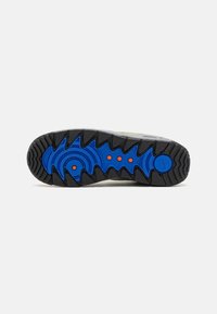 Semelle d'une basket avec un motif noir, bleu et orange conçu pour l'adhérence et la durabilité.