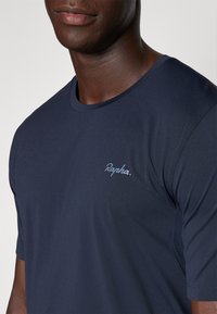 Marineblå t-shirt lavet af glat stof med rund halsudskæring og korte ærmer. Mærkenavnet "Rapha." er syet på brystet.