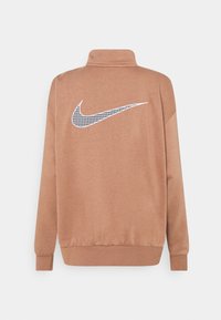 Brun fleecejacka med hög krage, med en stor svart och vit hundstooth Nike-logotyp på baksidan och elastiska muddars.