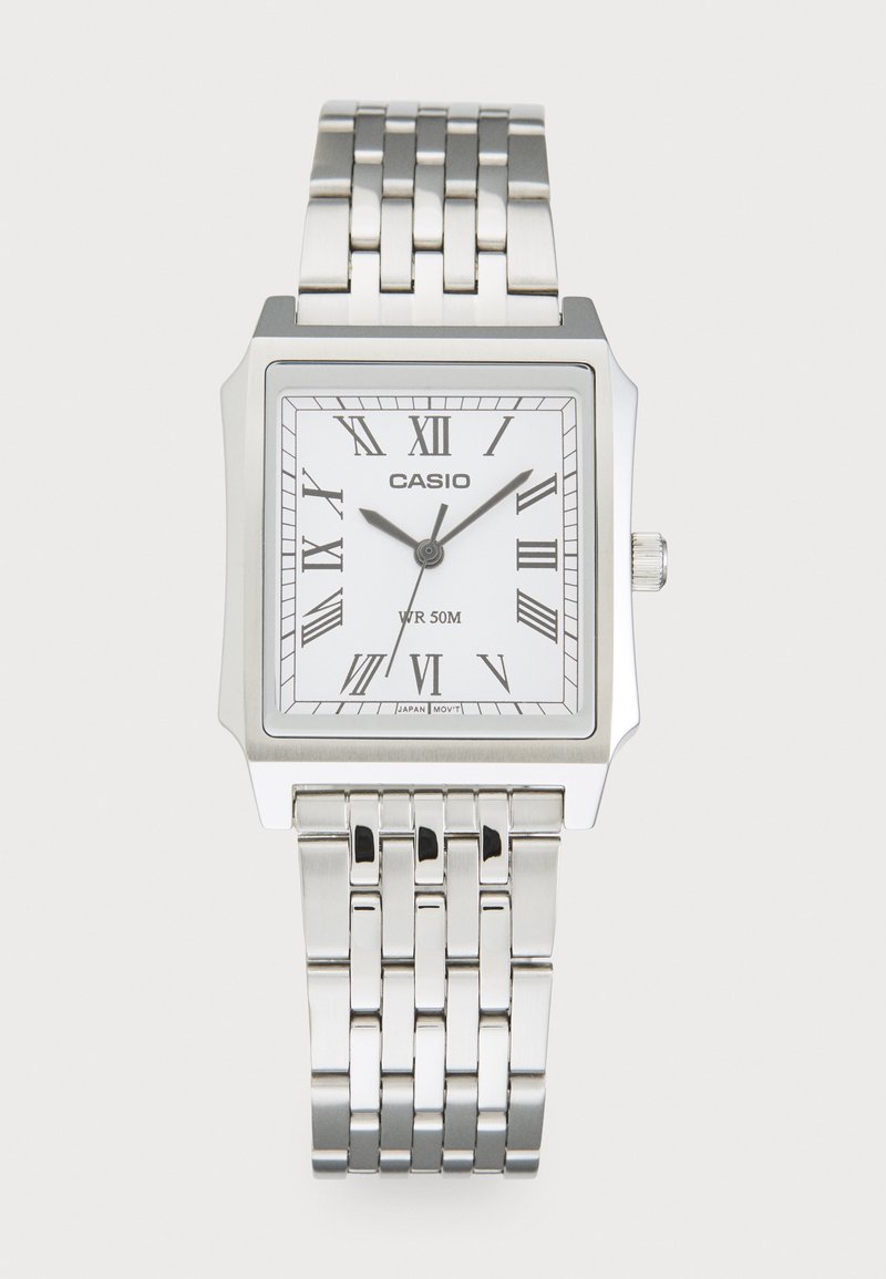 Montre en métal argenté avec un boîtier carré, un cadran blanc, des chiffres romains et un bracelet à maillons. Résistante à l'eau jusqu'à 50 mètres.