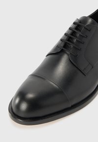 Black leather dress shoe with a smooth finish, lace-up design, rounded toe, and subtle stitching along the sole.