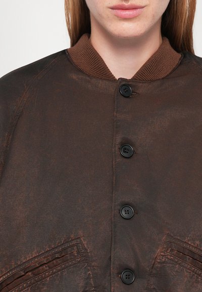 Brown button-up jacket with a ribbed collar, featuring a textured fabric and two angled pockets. Six black buttons down the front.