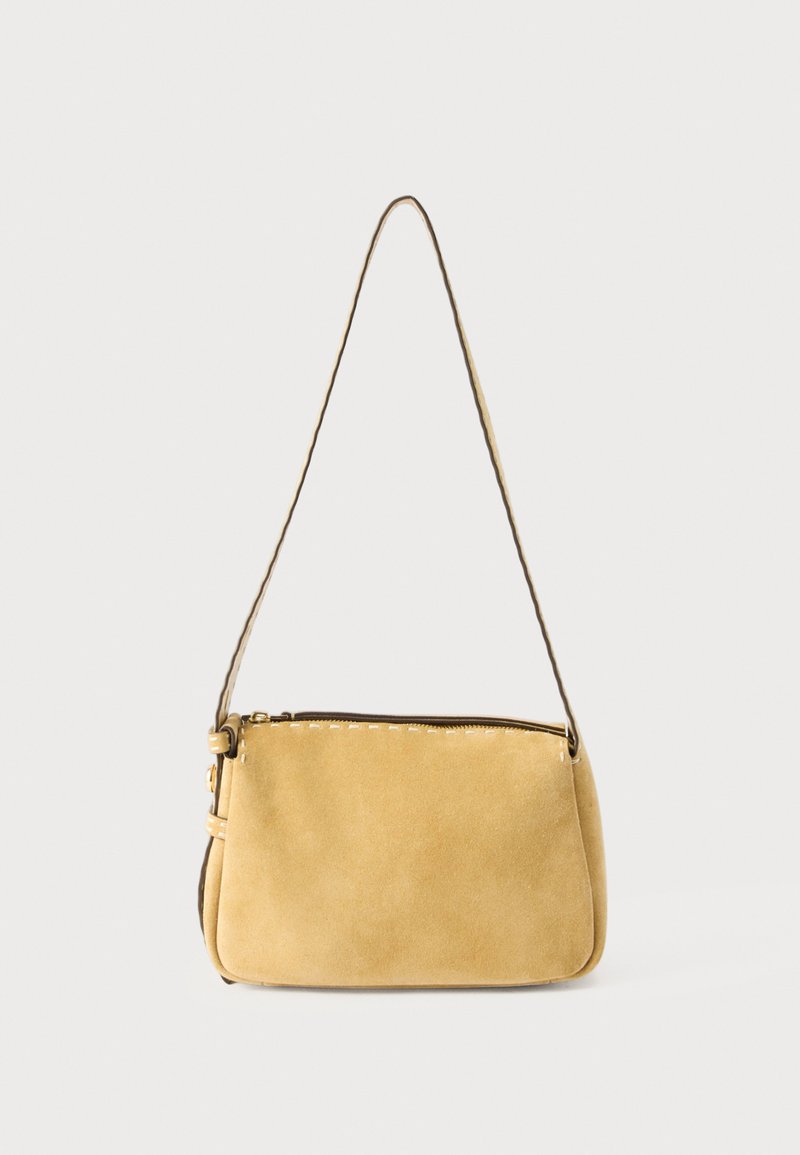Μικρή ώμου τσάντα από μουσταρδί κίτρινο σουέντ με λεπτό ιμάντα και φερμουάρ στην κορυφή, πάνω σε απλό φωτεινό φόντο.