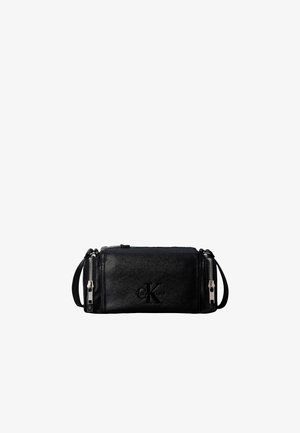 Sac bandoulière rectangulaire en cuir noir avec deux fermetures éclair argentées sur les côtés et logo Calvin Klein embossé sur le devant.