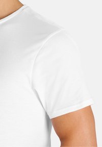 T-shirt bianca in cotone con colletto tondo e maniche corte. Tessuto liscio senza motivi o decorazioni visibili.