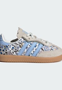 Baskets à motif floral avec une base blanche, des accents en daim bleu clair, des rayures bleues et une semelle en caoutchouc marron. Comprend un système de laçage.