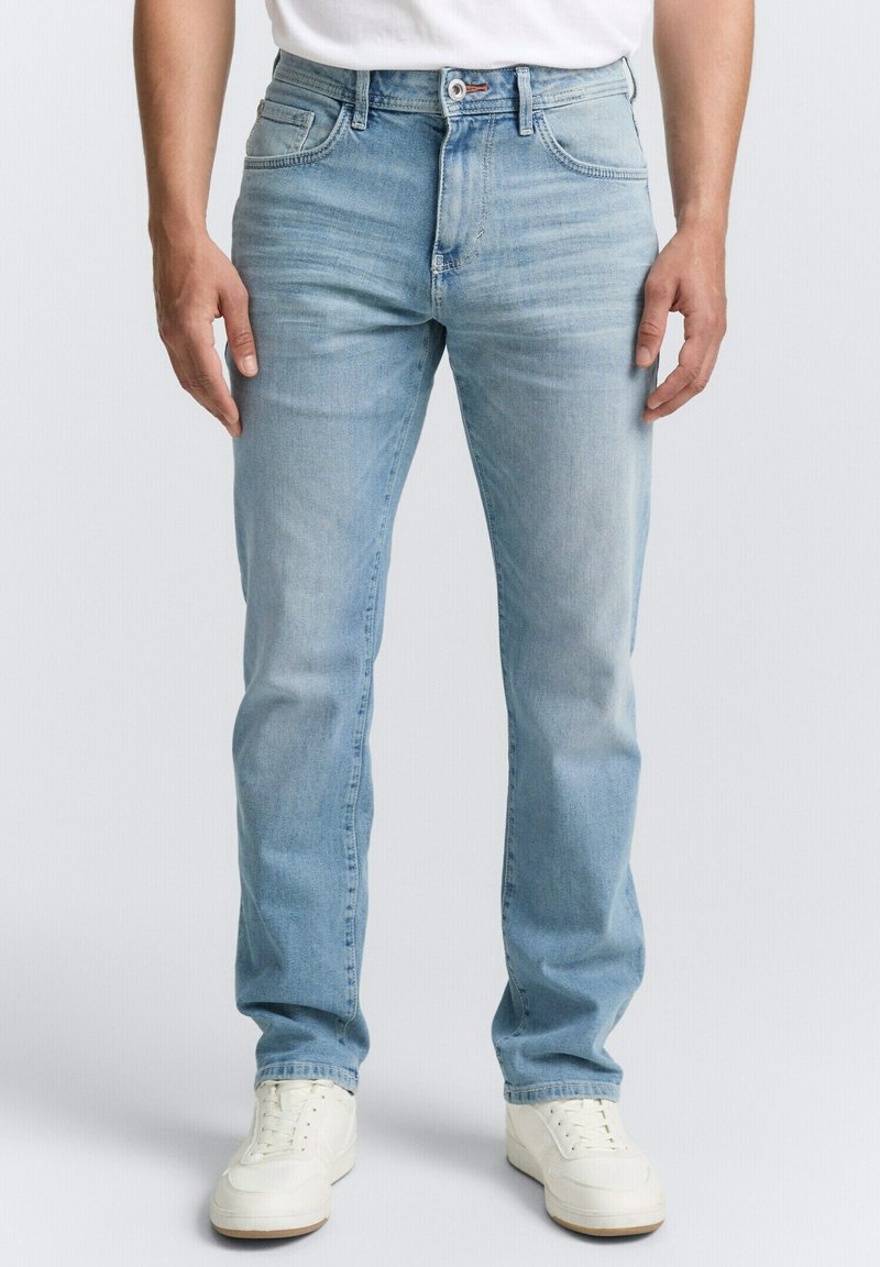 Lichtblauwe denim jeans met een rechte pasvorm, vijf zakken en een iets verouderd effect. Gepaard met witte sneakers.