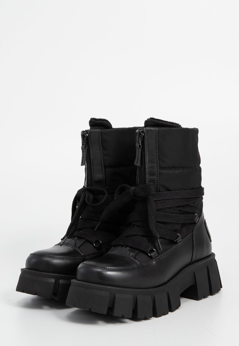 Schwarze Knöchelstiefel aus einer Kombination von glattem Leder und mattem Stoff. Runde Zehen, dicke Plateausohle, Schnürung vorne und zwei seitliche Reißverschlüsse.