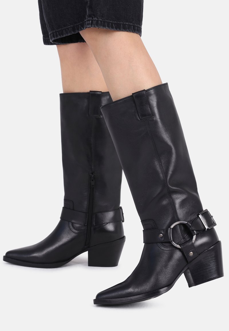 Czarne skórzane buty do kolan z kwadratowymi noskami, bocznym zamkiem błyskawicznym i dekoracyjnym paskiem z okrągłą klamrą. Lekko teksturowane wykończenie.