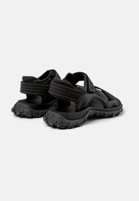 Svarta sandaler med en texturerad gummisula, med justerbara remmar och urklippsdesign för bra ventilation. Hållbart material och kraftig sula.