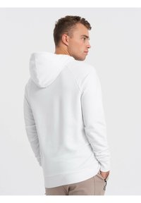 Sudadera blanca con capucha ajustable, puños y dobladillo acanalados, que presenta una textura suave y un diseño simple y minimalista.
